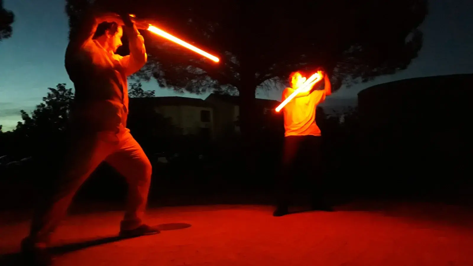 Combat de sabre laser en nocturne, lames rouges lumineuses au crépuscule.
